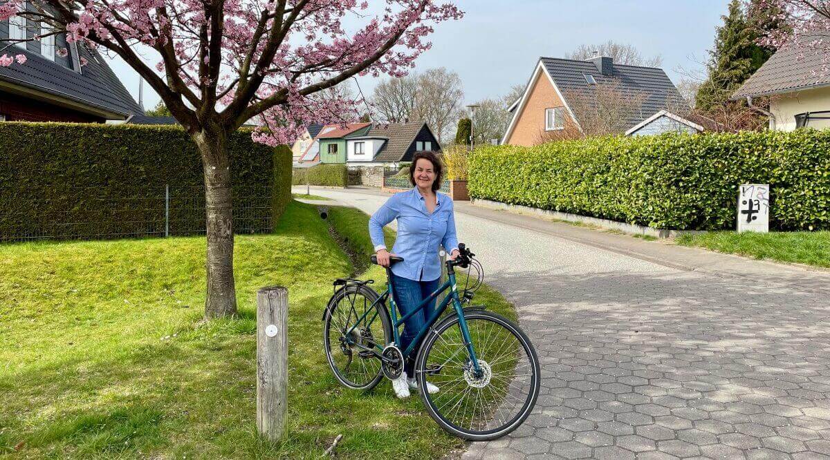 Nicole Theinert, Journalistin, mit dem Fahrrad im Frühling unter einem Baum